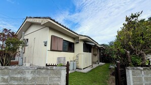Una casa de un piso con techo inclinado, un pequeño porche delantero y un camino de entrada pavimentado.