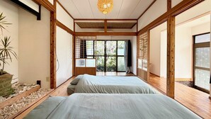 Una habitación tradicional japonesa con suelo de tatami, techo bajo y puertas correderas.
