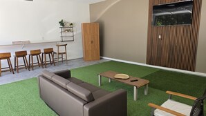 A modern living room with a sectional sofa, a small wooden table, and a TV mounted on a wooden panel wall. - A Trip to the Nursery Capital (McMinnville)