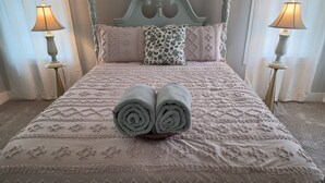 A bed with a decorative headboard, two bedside lamps, and rolled towels on the bed. - A Trip to the Nursery Capital (McMinnville)