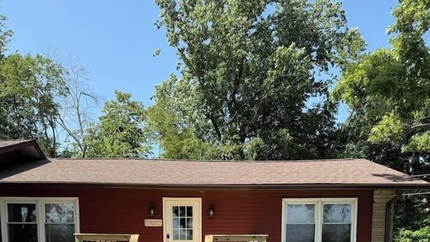 A single-story building with a front porch, a door, and two windows on the side. - The Reservoir House East (Andrews)