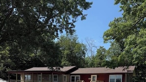 A motel with a gravel driveway, wooden deck, and a covered outdoor area. - The Reservoir House East (Andrews)