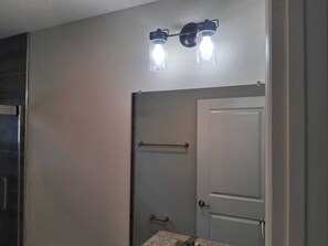 Ein Badezimmer mit Handtuchhalter, einer Tür und einer Wandleuchte.