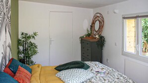 Een slaapkamer met een bed, een dressoir, een raam en een deur.