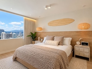 Ein modernes Schlafzimmer mit einem großen Bett, einem Nachttisch, einer Wanduhr und Blick auf die Stadt.