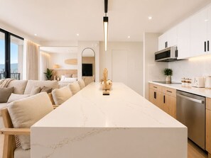 A modern kitchen with a marble countertop, wooden cabinets, and a built-in microwave. - 32F Luxury Waikiki Ocean Suite w/ Parking (Honolulu)