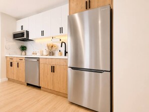 A modern kitchen with stainless steel appliances, wooden cabinets, and a dishwasher. - Luxury Waikiki Ocean Retreat 32F w/ Parking (Honolulu)