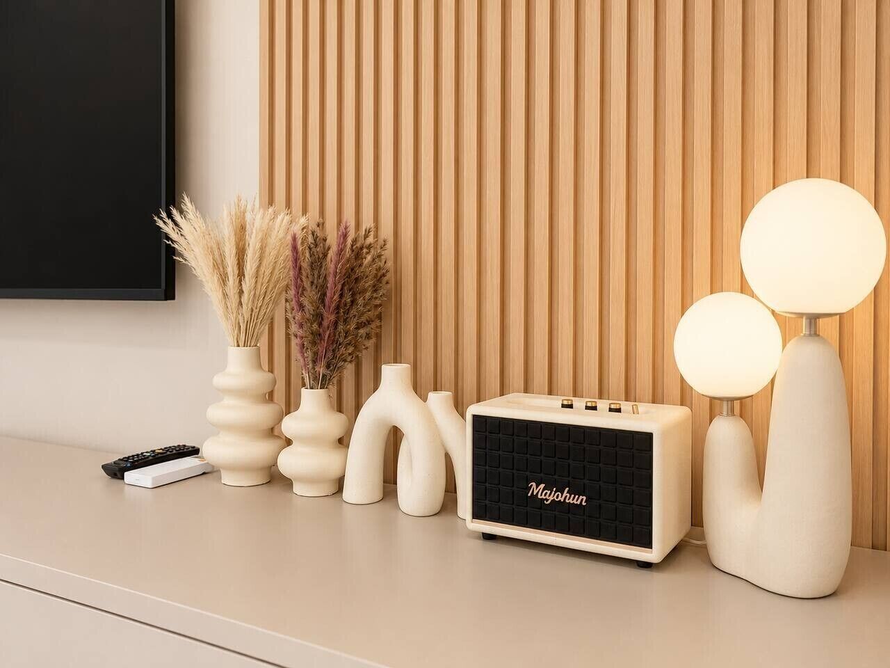 Een modern interieur met een flatscreen televisie, een witte radio, decoratieve vazen en twee bolvormige lampen.