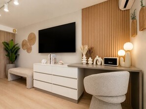 Un salon moderne avec un téléviseur à écran plat, un meuble blanc, un banc et un fauteuil.