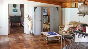 A living room with a sofa, a coffee table, and a dining area with a table and chairs. There is a vase with flowers on a stand, and a television in the background. - 1 bedroom nice home in Carry le Rouet (Carry le Rouet)