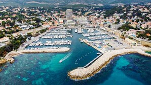 An aerial view of a marina with boats docked, surrounded by residential buildings and a prominent hotel structure. - 1 bedroom nice home in Carry le Rouet (Carry le Rouet)