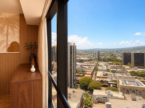 A room with a large window overlooking a cityscape, a wooden desk, and a vase. - Luxe City Retreat – Chic & Cozy Stay Free Parking (Honolulu)