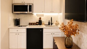 Una cucina moderna con mobili bianchi, una lavastoviglie nera, un forno a microonde e una macchina per il caffè.