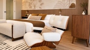 Una camera da letto moderna con un letto, due divani bianchi, un armadietto in legno e una parete decorata con motivi di palme.