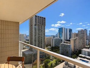 A balcony with a view of high-rise buildings, a chair, and a pool. - Luxe Island Retreat – Modern Coastal Design (Honolulu)