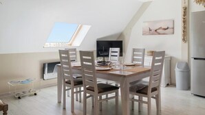 Een eetruimte met een hoge plafond, een tafel gedekt voor vier personen, en een uitzicht op de lucht door een dakraam.