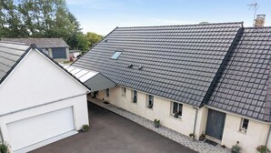 Een woonhuis met schuin dak, een garage en een kleine tuin met plantenpotten.