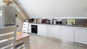 Een moderne keuken met witte kastjes, een roestvrijstalen koelkast, een vaatwasser, en diverse apparaten op het aanrecht.