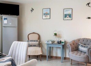 A room with a bed, a chair, a table, and a refrigerator. - Gîtes de France® - Gîte Terre (LE TREPORT)