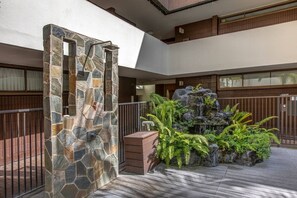 A stone archway, a small waterfall feature, and a wooden deck. - Honolulu City Oasis 2BR with Free Parking (Honolulu)
