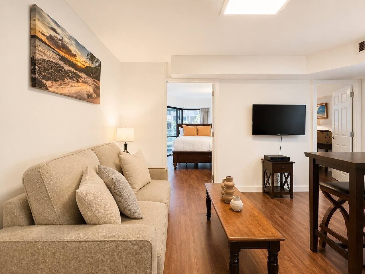 A living room with a sofa, a coffee table, a TV, and a dining area.