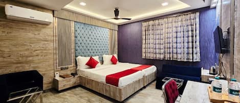A modern hotel room with a large bed, a desk, a chair, and a television.