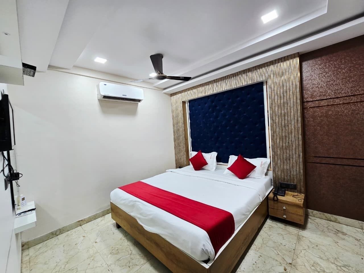 Un dormitorio con cama, ventilador de techo, equipo de aire acondicionado, mesita de noche y armario de madera.