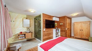 Una camera da letto con un letto, un armadio in legno, una TV e un bagno con doccia in vetro.