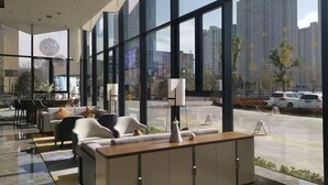 Un vestíbulo moderno con amplias ventanas, zona de estar y mostrador de recepción.