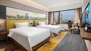 Habitación de hotel con dos camas, un escritorio, una silla, un televisor y vistas a la ciudad.