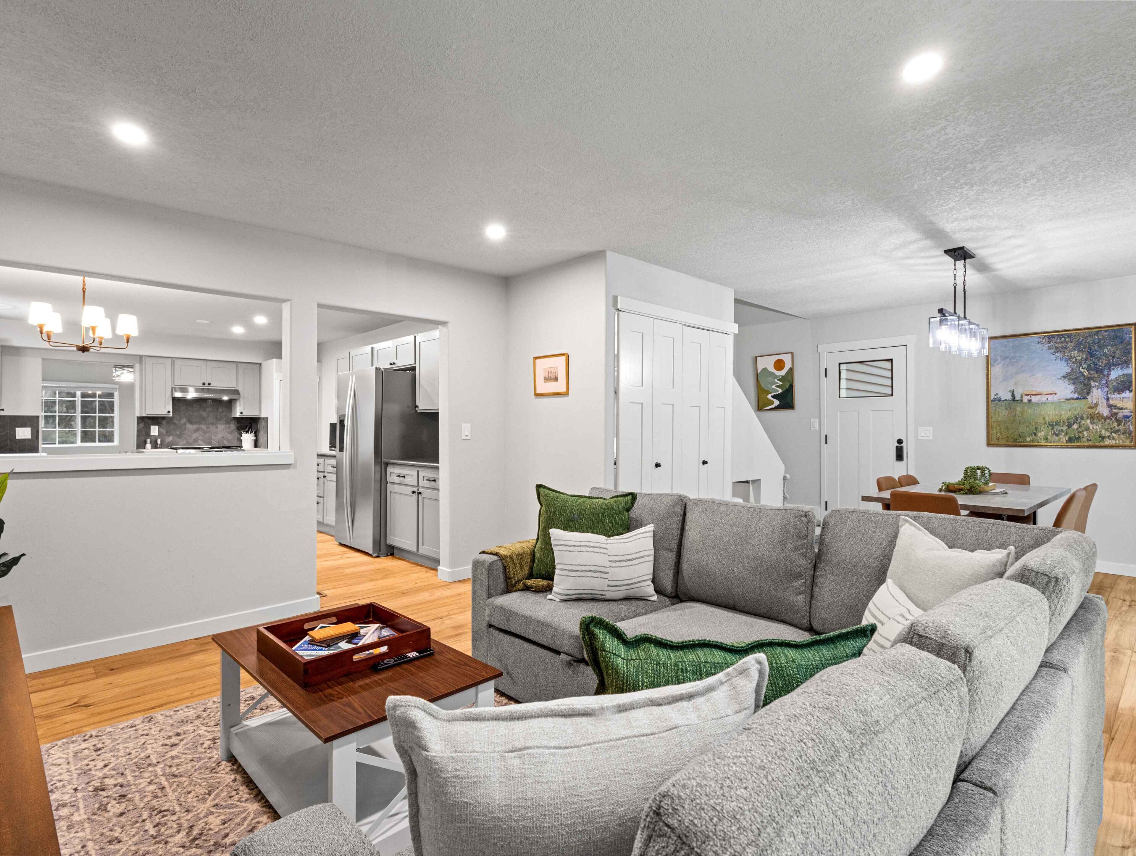 A modern living room with a grey sofa, a coffee table, and a dining area with a table and chairs.