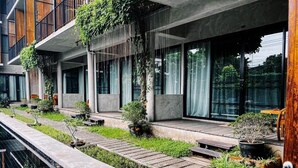 Un edificio moderno con jardín en la azotea, asientos exteriores y una piscina.