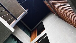 Un edificio moderno con paredes de hormigón, listones de madera y un ventanal visible.
