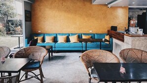 Un interior moderno con un sofá azul, sillas de mimbre, una mesa y un ventilador de techo.
