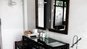 Un baño con tocador de madera oscura, un espejo grande y un perchero para toallas.