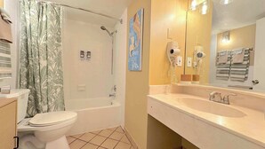 A bathroom with a shower, toilet, and sink, including a towel rack and a mirror. - Tropical Tranquility - Oceanside Retreat w/ Pool (Daytona Beach)