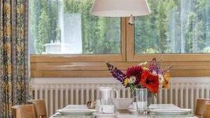 Una mesa de comedor con sillas, una lámpara y un arreglo floral.