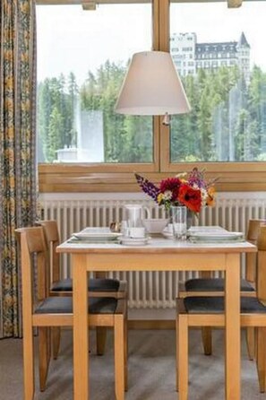 Ein Esstisch mit Stühlen, einer Lampe und einer Blumenkomposition.