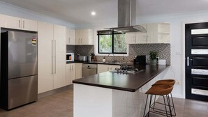 Une cuisine moderne dotée d’un réfrigérateur en acier inoxydable, d’un îlot central et d’une cuisinière noire.