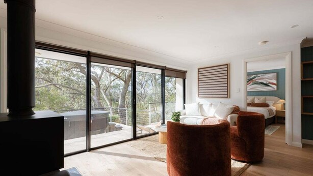 Un salon moderne avec une cheminée, de grandes portes-fenêtres coulissantes donnant sur un balcon, un canapé et un lit.