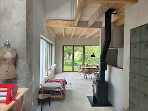 A room with a large window, a wooden ceiling, a fireplace, and a mannequin.