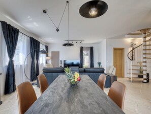 Un salon moderne avec une table à manger, un canapé et un escalier.