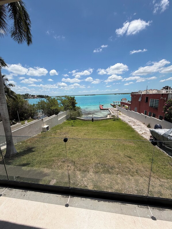 A view of a coastal area with a grassy lawn, a red dock, and a building with a red facade.