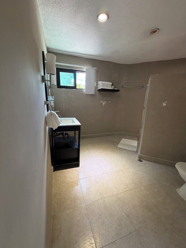 A bathroom with a toilet, sink, and shower area.