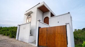 A modern building with a white exterior, a wooden door, and a small window. - Casa Vara Uluwatu (Badung)
