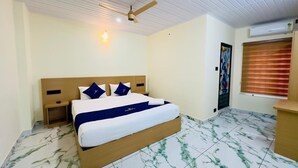 A hotel room with a bed, a nightstand, a ceiling fan, an air conditioning unit, and a window with blinds. - Breeza Residency (Thiruvananthapuram)