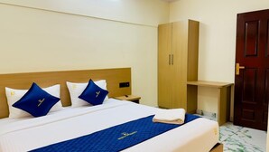 A hotel room with a bed, a wardrobe, a desk, and a door. - Breeza Residency (Thiruvananthapuram)