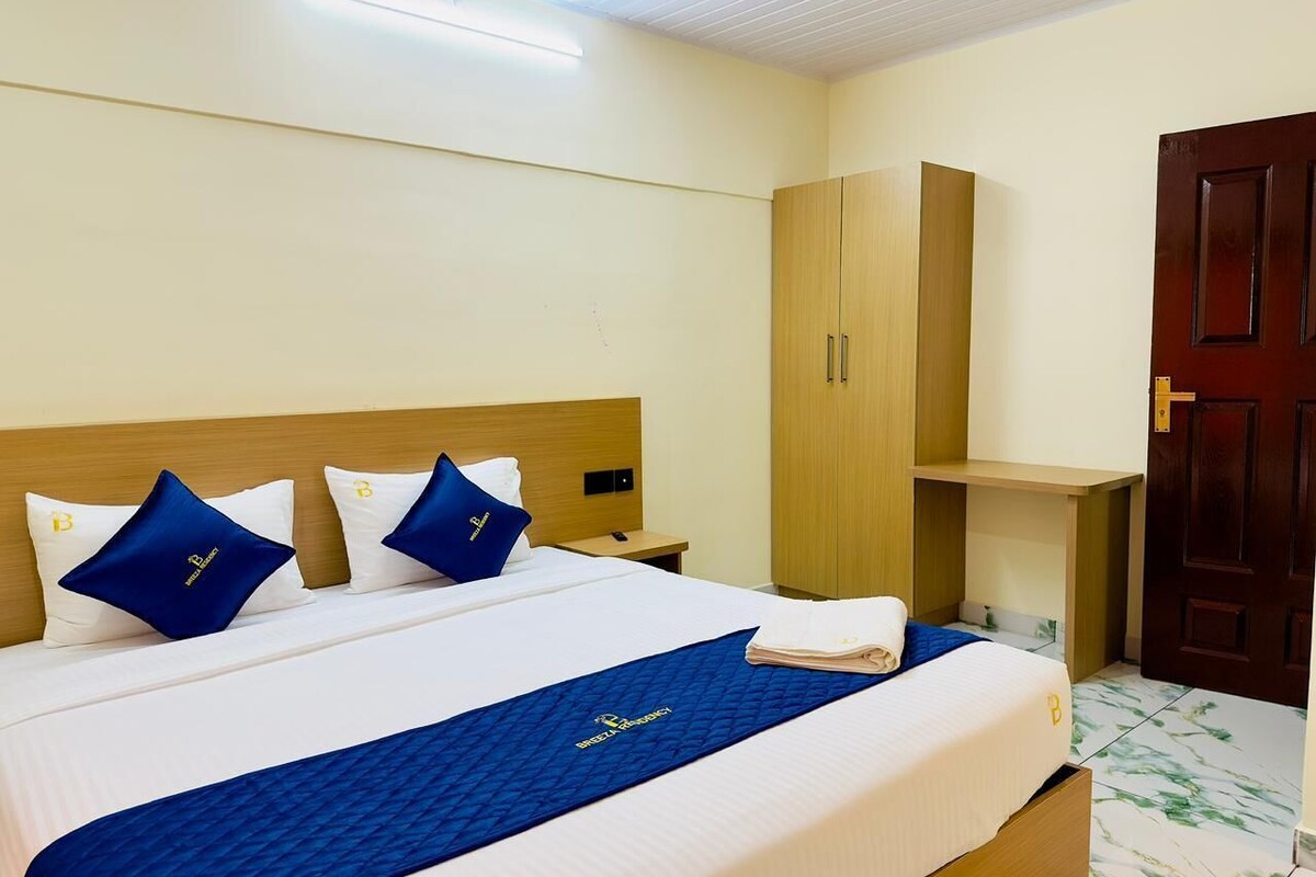 A hotel room with a bed, a wardrobe, a desk, and a door.