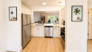 Une cuisine moderne avec des meubles blancs, des appareils électroménagers en acier inoxydable et un plancher en bois.