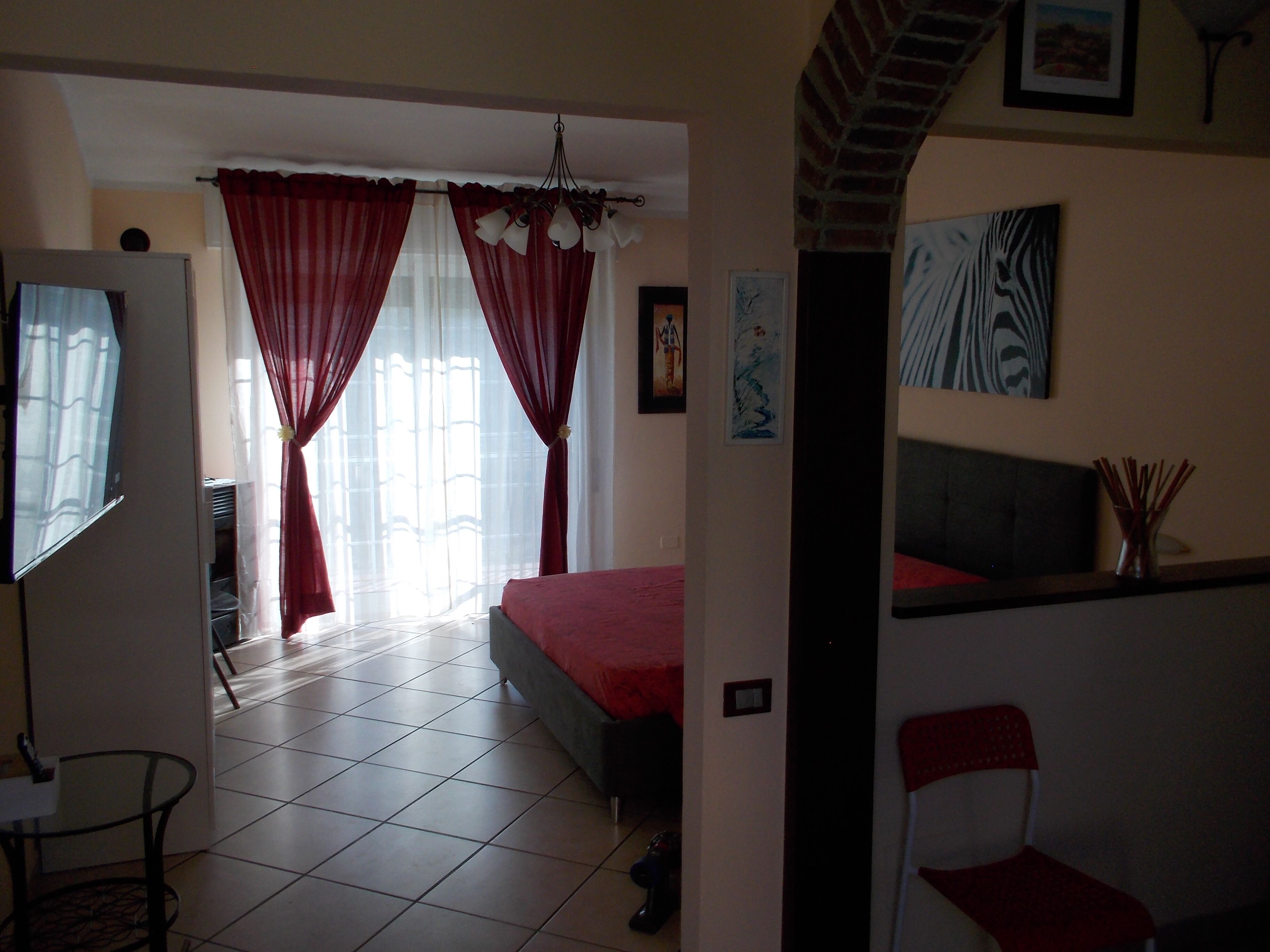 Une chambre à coucher avec un lit, une chaise, un bureau et une fenêtre avec des rideaux.